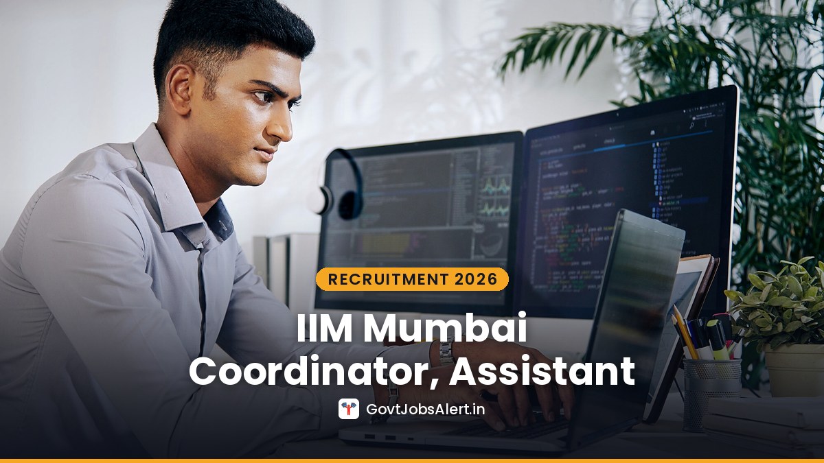 A young Indian professional working at a desk with two monitors — IIM Mumbai Recruitment 2026 Weekend MBA Coordinator, Assistant and Technical Support Staff
