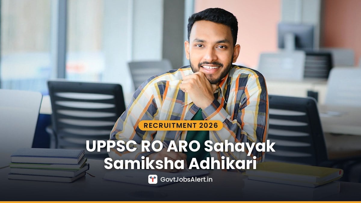 A young Indian man studying at his desk with a stack of books — UPPSC RO ARO Samiksha Adhikari Recruitment 2026